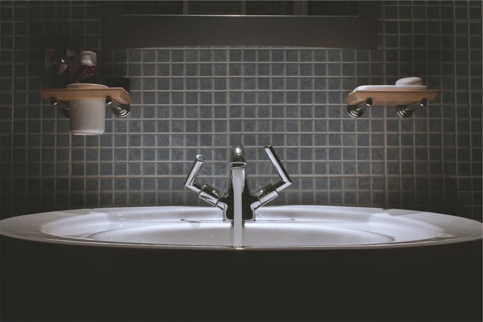 A clean basin and tapware against dark bathroom tiles